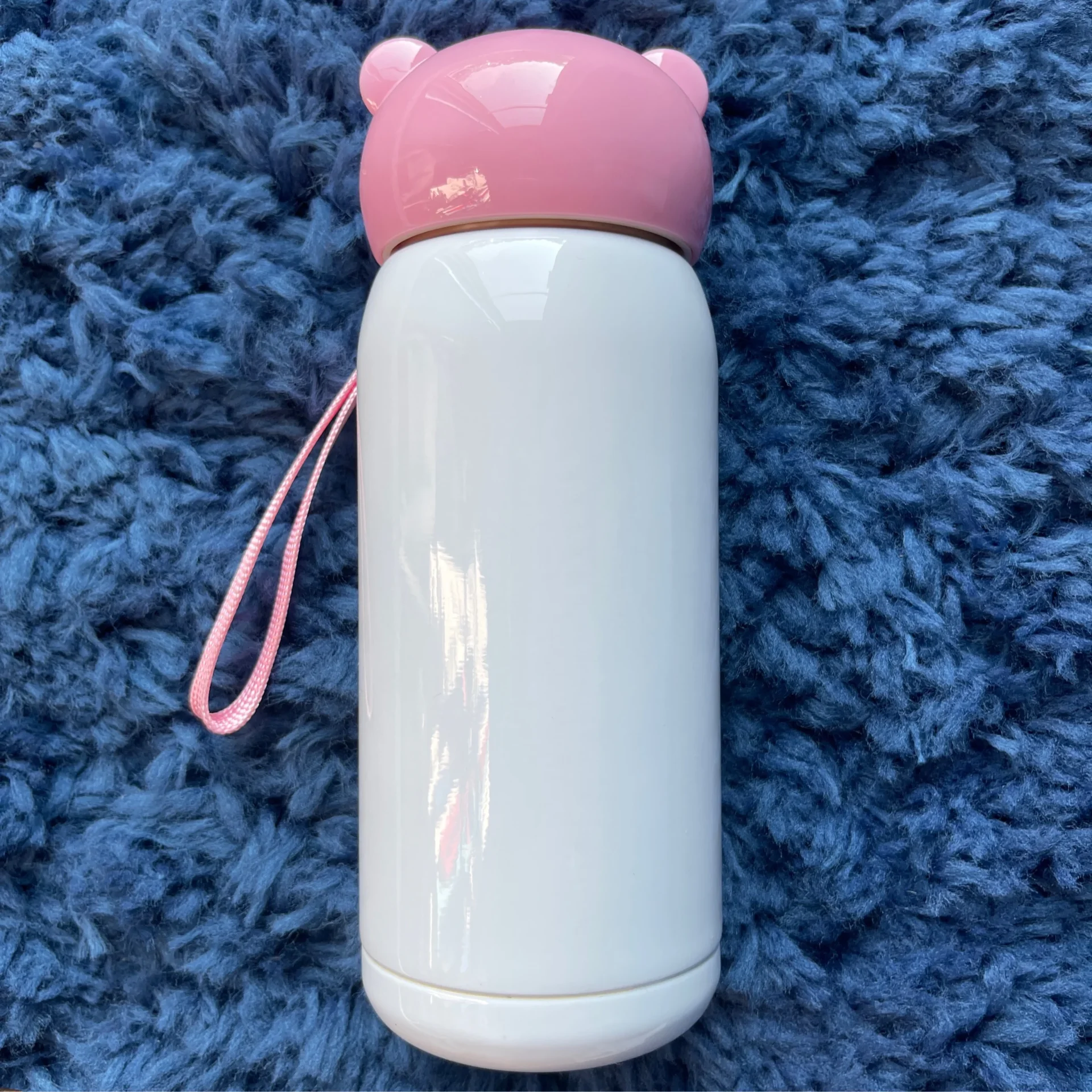 A white water bottle with pink lid on blue carpet.