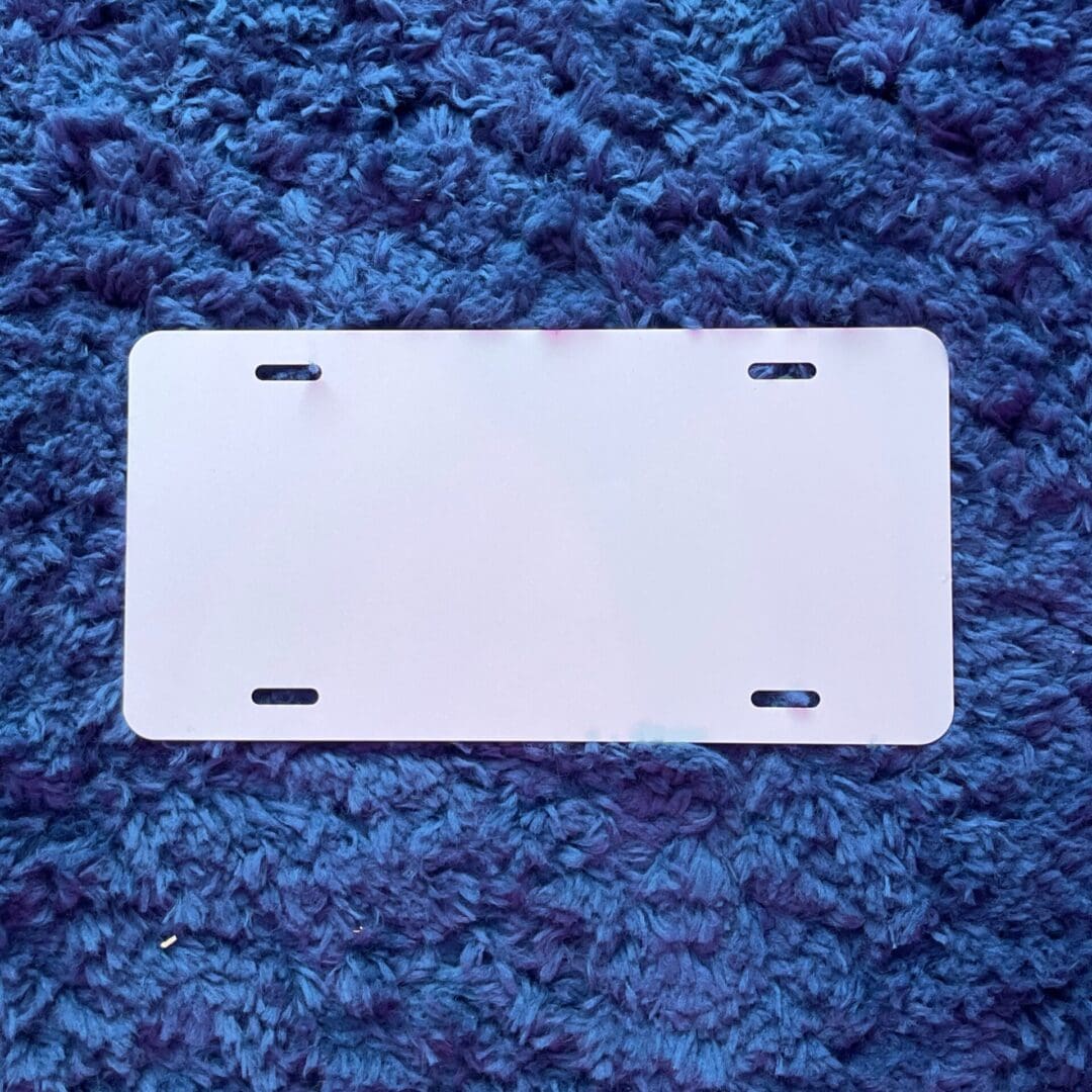 A white license plate sitting on top of blue carpet.